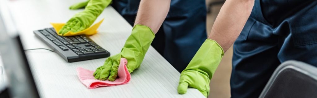 partial view of cleaners in rubber gloves cleaning office desk and computer keyboard ajax cleaner, toronto west